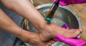 Voetverzorging met een kwast en handschoenen boven een waterbad