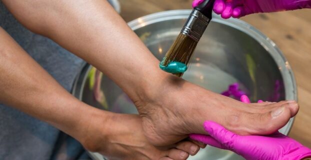 Voetverzorging met een kwast en handschoenen boven een waterbad